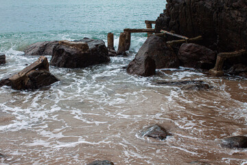 Close-up of foamy sea water splashing gently over smooth coastal rocks. A tactile glimpse into the...