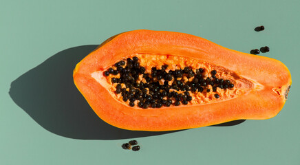 Papaya fruit over green background, fresh exotic fruits with seeds. Halved fresh organic Papaya exotic fruit art design, close up. Top view 