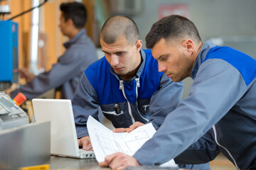 two construction workers holding plans discussing project