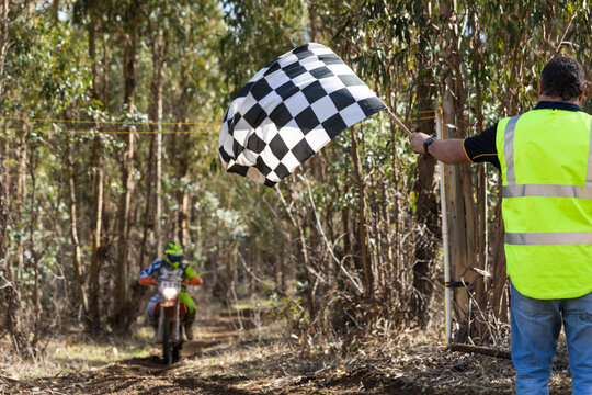 Race official waving chequered flag at finish of motorcycle race