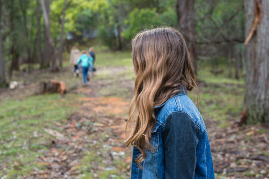 teen girl lagging behind a group of kids in a forest