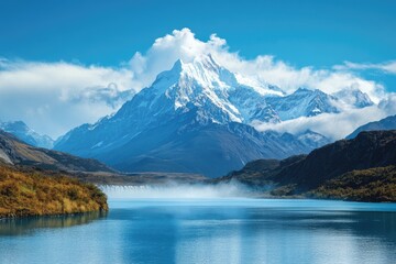 Majestic mountain range overlooking a serene lake.  Snowy peaks rise above a placid body of water, framed by lush greenery
