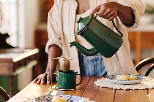 Brazilian woman preparing traditional breakfast with strained coffee and cheese bread rolls