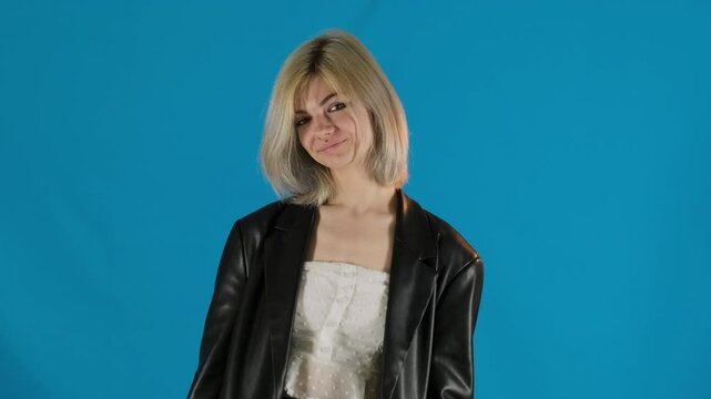 Joyful woman in leather jacket swings around smiling. Young blonde with bob develops hair expressing emotion happiness slow motion