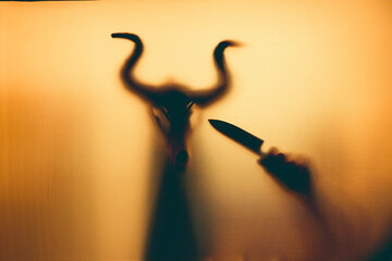 Horror, halloween background - Shadowy figure with horns behind the glass