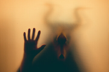 Horror, halloween background - Shadowy figure with horns behind the glass
