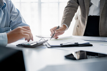 Two financier analyzing on data paper using calculator at the office workplace