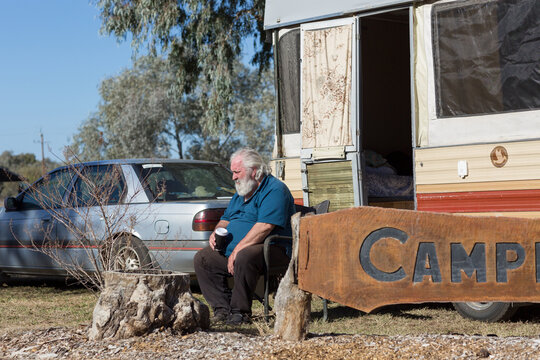 Old guy sitting outside his vintage pop-up caravan
