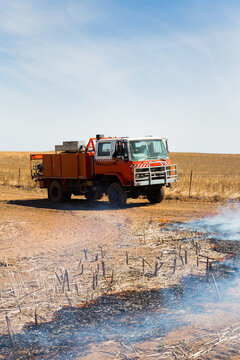 Fire truck with burnt canola windrow and smoke