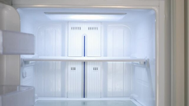 Modern white open refrigerator close-up with empty shelves, front view.