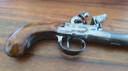 old ancient antique gun with openwork wood carvings and handle firearm pistol weapon on wooden...