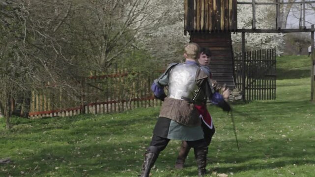 Two medieval knights dramatic sword fighting duel outside fort gates