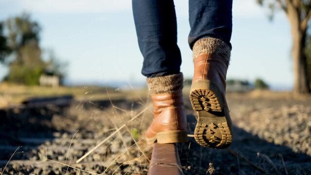 Booted feet walking away on railway tracks