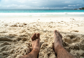 Bare feet resting in warm sand on tropical beach, symbolizing summer relaxation, freedom