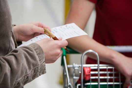 Young woman holding shopping list in supermarket