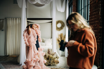 Woman in pink ruffled robe poses as photographer checks camera