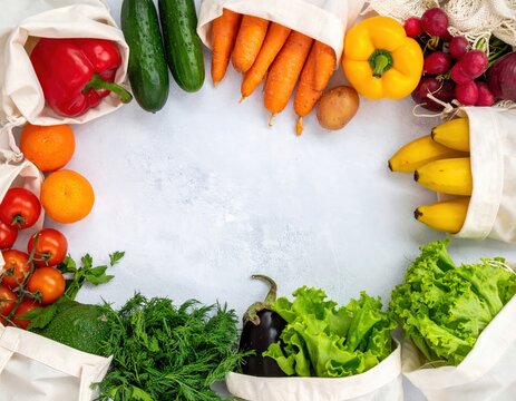 A vibrant circle of assorted vegetables and fruits, including bright red tomatoes, leafy greens, yellow bell peppers, and ripe bananas, arranged on a clean white surface.