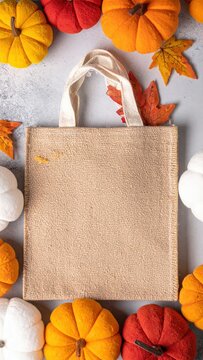 A stylish jue bag filled with vibrant orange pumpkins and soft, fluffy white cotton, creating a cozy autumn vibe perfect for seasonal decor.