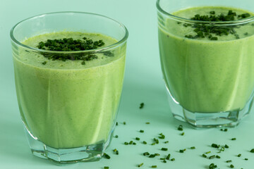 Close-up view of two glasses of blended chives and buttermilk, topped with chopped chives....