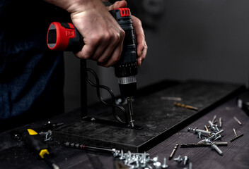 Man Screws Bracket To Shelf With Screwdriver, Hands In Close-Up