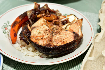 A piece of fried cod fish with boiled rice lies on a plate.