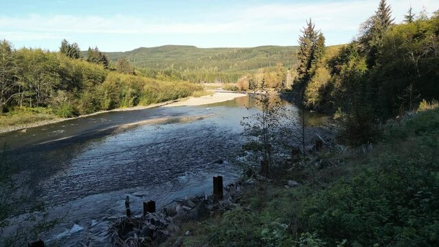 Drone footage soaring over a peaceful riverbend surrounded by dense evergreen forest and rolling hills in the Pacific Northwest