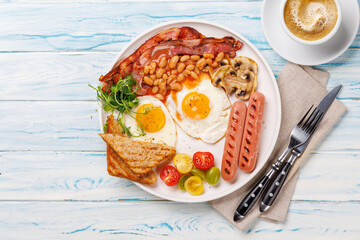 A classic breakfast plate featuring sunny-side-up eggs, crispy bacon, sausages, and fresh tomatoes
