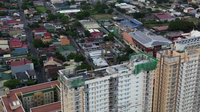 Aerial orbit of crane and construction site atop high-rise condominium rooftop surrounded by residential area at Marikina City, Philippines