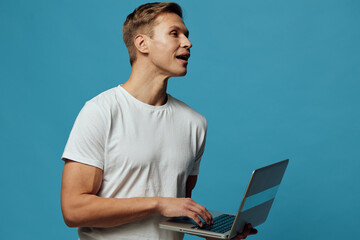 young caucasian man working with laptop speak in video call wear white t-shirt isolated blue...