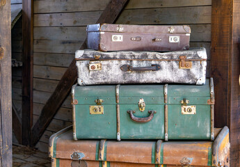 stack of old, weathered suitcases and trunks arranged in a rustic wooden setting. Each piece shows signs of age and use, giving the scene a strong vintage and nostalgic feel. Perfect for themes relate © Adam