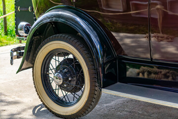 Detailed close-up of a classic vintage car wheel with a whitewall tire and curved fender. The shiny...