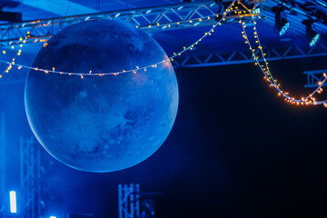 Planet-themed decor at BALTA event with a glowing blue orb suspended under twinkle lights in a dramatically lit, space-inspired atmosphere..