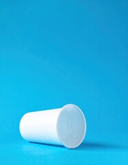 A simple white plastic cup sits prominently against a vibrant blue background, showcasing its smooth surface and clean lines, perfect for casual settings.