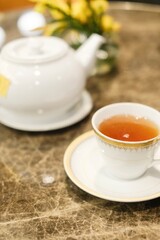 
Close-up of a fine bone china teacup with gold trim and a pot of Taiwanese tie guan yin oolong tea at the lounge of Montien Surawong, a hotel in Silom - Bang Rak, Bangkok, Thailand