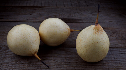 Three pears are lying on a wooden board. Snow pear.