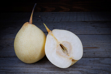 Whole and half ripe pear on a wooden surface. Snow pear.