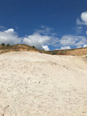 A wide shot of a sandy hill with a bright blue sky and white clouds above. Ideal for travel, outdoor activities, and nature-themed projects.