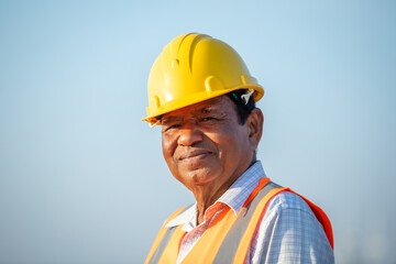 Senior engineer smiling while standing in wind farm. Renewable energy industry, portrait
