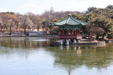 Traditional Korean Pavilion on Serene Lake in Winter Landscape. Scenic view of a Korean-style pavilion with a green tiled roof situated on a peaceful lake.
