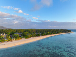 The coastline of Le Morne, Mauritius curves along calm turquoise waters with villas nestled in...
