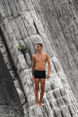 Chico joven tatuado en playa de rocas, Playa de la Arnía, Santander, España
