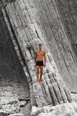 Chico joven tatuado en playa de rocas, Playa de la Arnía, Santander, España