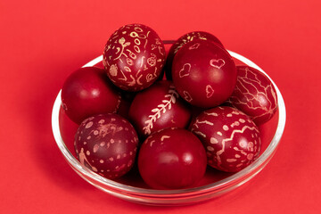 Red-painted Easter eggs on a glass plate on a red background