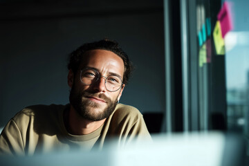 Obraz premium Portrait of young bearded man wearing glasses in modern office with post-it notes on glass wall