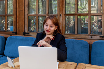 Smiling woman working on laptop at cozy outdoor cafe