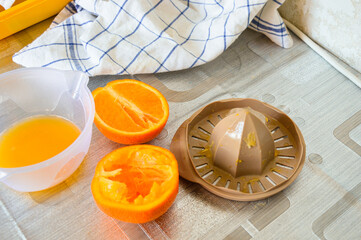 Fresh orange halves with juicer and bowl on kitchen table. Preparing homemade juice, healthy...