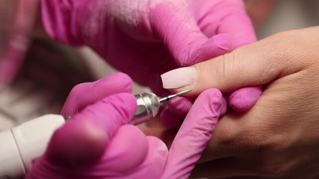 Electric File Manicure for French Nail Style, Close-up of a nail technician using an electric nail drill to shape and clean nails.