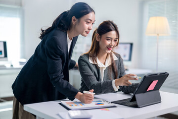 Two women are working together on a computer, one of them is smiling
