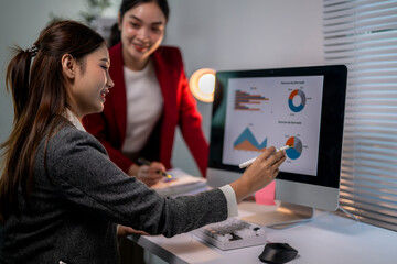 Two women are looking at a computer monitor with graphs on it