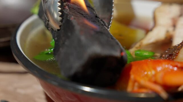 Traditional fish soup with vegetables, herbs and crayfish in enamel bowl, close-up of hot clear broth. Ukrainian yushka with potatoes, parsley and smoked fish served in rustic style.
